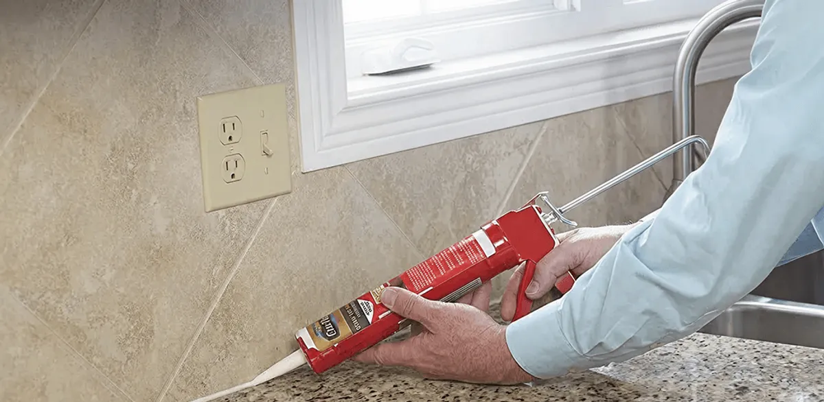 Handyman applying caulk along a kitchen backsplash and countertop seam in Albuquerque, NM